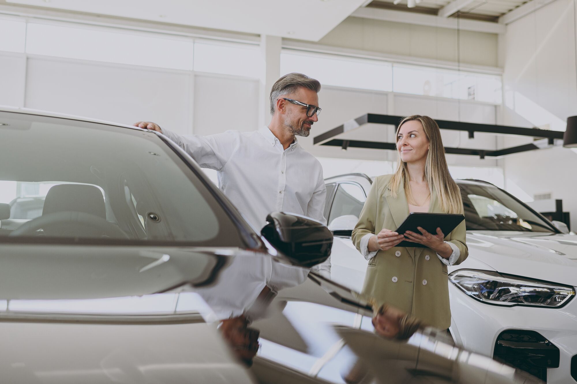 Adult man customer male buyer client wear shirt consult with salesman hold documents choosing auto want to buy new automobile in car showroom vehicle salon dealership store motor show. Sales concept